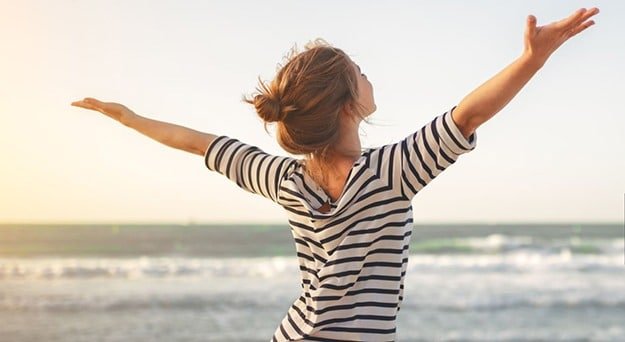 femme exprimant sa vitalité face à la mer après un drainage lymphatique